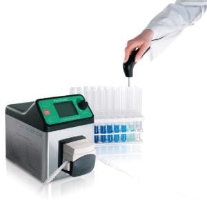 Hand using a pipette near a laboratory analyzer with test tubes.