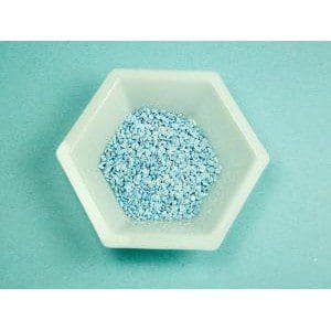 Hexagonal dish filled with small blue pellets on a teal surface.